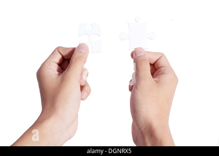 Two hands holding puzzle pieces and connecting them Stock Photo