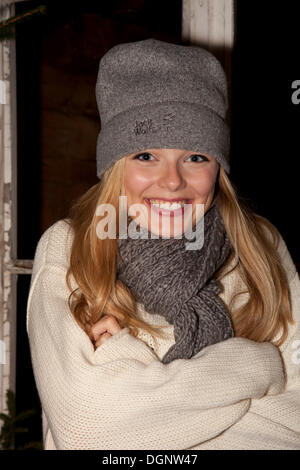 Smiling young woman wearing a cap and a scarf standing in front of a hiking hut Stock Photo