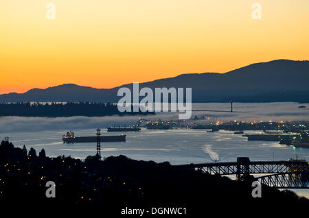 Vancouver, British Columbia, Canada - October 23, 2013:  At sunset, heavy fog rolls into Vancouver harbour, and Burrard Inlet, passing under the Lion's Gate Bridge and moving alongside Stanley Park. Stock Photo