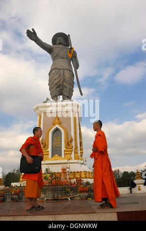 Monument of the last King Chao Anouvong in Vientiane on the Mekong River, two Buddhist monks having a chat in front of it, Laos Stock Photo