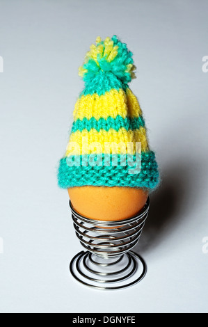 Boiled egg in a coiled metal eggcup topped with a knitted egg cosy. Stock Photo