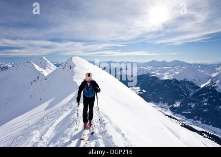 Cross-country skier ascending Ellesspitze Mountain, here on the summit ridge with Ridnauntal Valley below Stock Photo