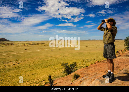 Man looking through binoculars into Damaraland, Namibia, Africa Stock Photo