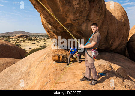 Young man hanging in a climbing rope, Bogenfels, Spitzkoppe area, Namibia, Africa Stock Photo