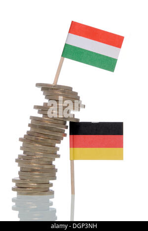 Wobbly stack of Euro coins supported by a German flag, a Hungarian flag on top, symbolic image for financial crisis of the Euro Stock Photo