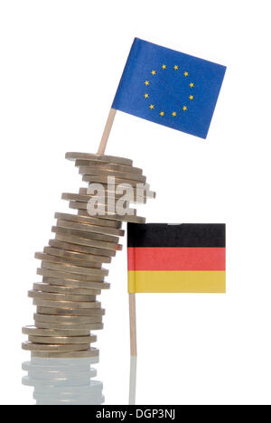 Wobbly stack of Euro coins supported by a German flag, a Euro flag on top, symbolic image for financial crisis of the Euro Stock Photo