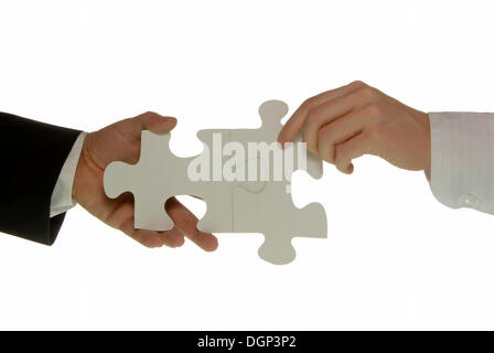A business man and a business woman holding two matching jigsaw puzzle pieces, symbolic image for cooperation Stock Photo