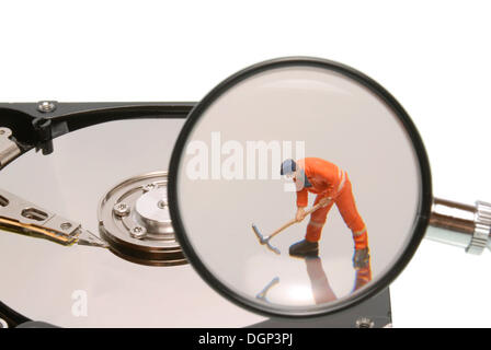 Small construction worker figure on a hard drive with magnifying glass, symbolic image for working on a data medium Stock Photo