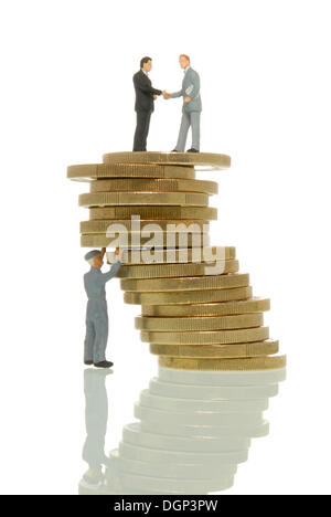 Worker figure propping up a wobbly stack of Euros with two business man figures on top, symbolic image, Euro crisis at the Stock Photo