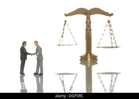 Miniature businessmen figures shaking hands in front of a balanced scale, symbolic image for balanced business Stock Photo