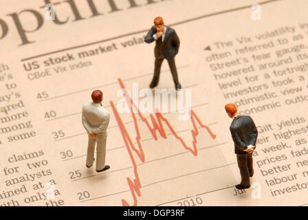 Miniature businessmen figures standing on a stock market chart Stock Photo