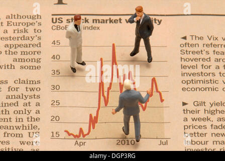 Miniature businessmen figures standing on a stock market chart Stock Photo