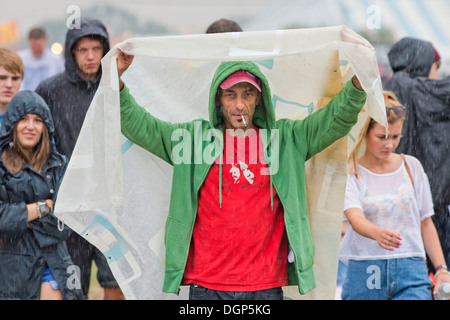 The Reading Festival - a man improvises some shelter from the rain Aug 2013 Stock Photo