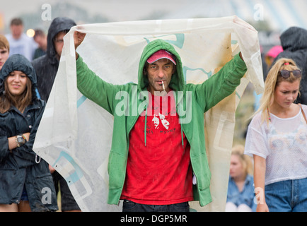 The Reading Festival - a man improvises some shelter from the rain Aug 2013 Stock Photo