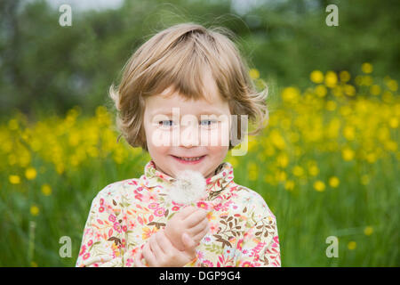Happy girl holding a dandelion clock in her hand, portrait Stock Photo