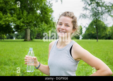 Young woman holding a bottle of mineral water, after working out