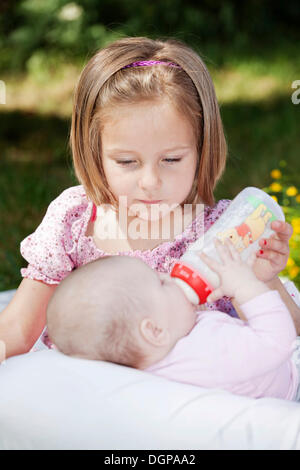 https://l450v.alamy.com/450v/dgpaa2/girl-4-feeding-a-baby-with-a-bottle-dgpaa2.jpg