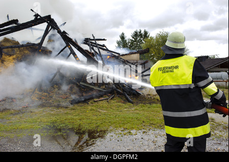 firefighter in action at burning house Stock Photo