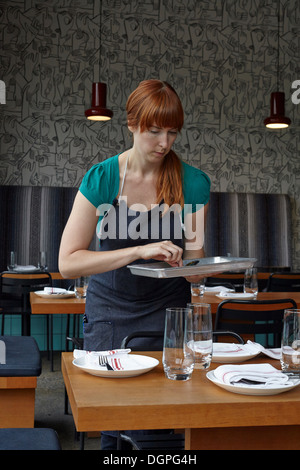 Mid adult woman preparing table in restaurant Stock Photo