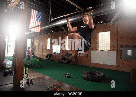 Bodybuilder doing pull up on bar in gym Stock Photo