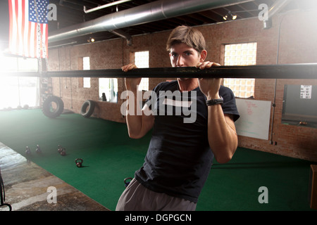 Bodybuilder pulling up on bar in gym Stock Photo