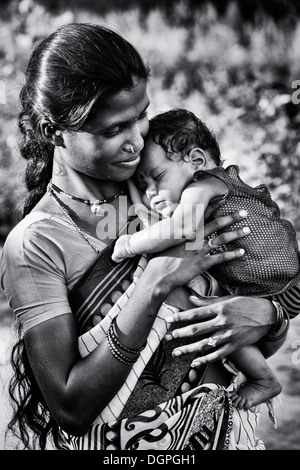 Happy lower caste Indian woman cradling her sleeping baby. Andhra Pradesh, India . Monochrome Stock Photo