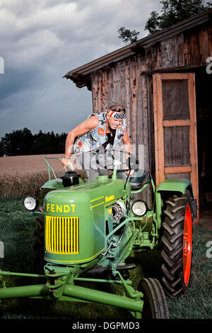 Man climbing onto a vintage tractor Stock Photo