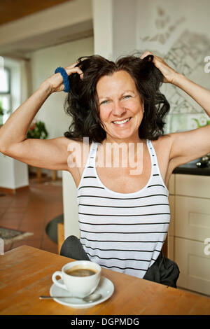 Woman having breakfast running her hands through her hair Stock Photo