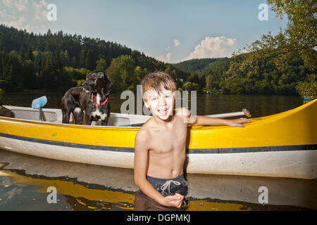 Boy with his canoe, his hunting dog, mongrel, standing in the canoe Stock Photo