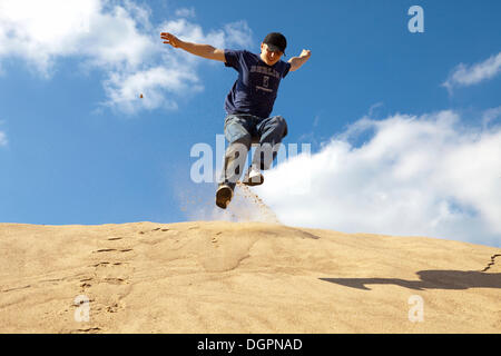 Young man jumping down a sand hill, Oettingen, Bavaria Stock Photo