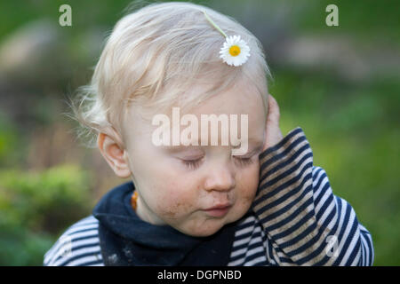 Small tired boy with a daisy on his head Stock Photo