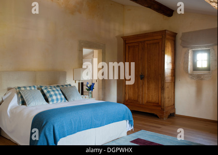 Rustic bedroom with French wooden cupboard and bed with Jane Saachi blanket Stock Photo