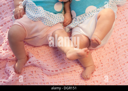 Baby feet in motion. Twins lying on a pink blanket. Stock Photo