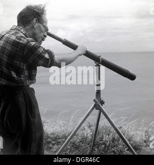 Historical picture, 1950s showing a land surveyor using a telescope on the Island of Lundy, in the Bristol Channel, England, Stock Photo