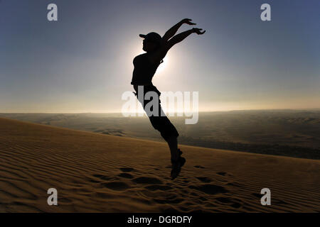 Woman leaping into the air in the desert, Nazca, Atacama Desert, Peru, South America Stock Photo