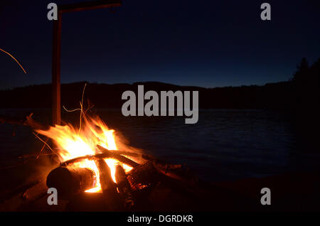Campfire with cooking apparatus on a lake at night Stock Photo
