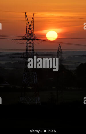 High-voltage transmission line in front of the rising sun, near Rendsburg, Schleswig-Holstein Stock Photo