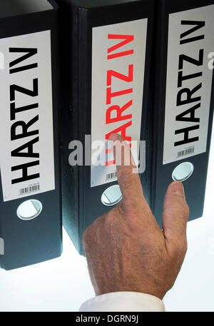 Hand pointing to a ring binder labeled Hartz IV, German term for long-term unemployment benefits, symbolic image Stock Photo