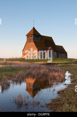 The Church of St Thomas a Becket, in Fairfield, Kent; reflected in the marshes at sunset. Stock Photo