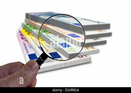 Stack of euro banknotes under a magnifying glass, symbolic image, observation of the euro Stock Photo