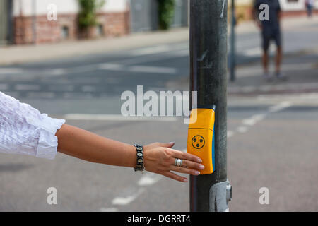 Woman pushing a button for visually impaired people at a pedestrian crossing, Hesse Stock Photo