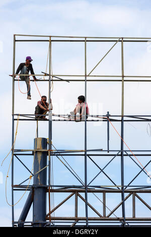 Unsecured workers assembling scaffolding, Banjar Kertabuana, Denpasar, Bali, Indonesia Stock Photo
