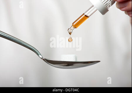 Pipette dripping medicine onto a sugar cube on a spoon Stock Photo
