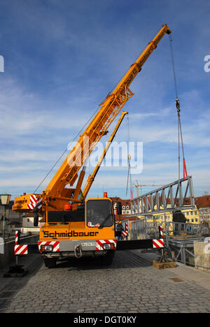 Two cranes lifting steel beams on Steinerne Bruecke, a stone bridge, symbol of Regensburg, Bavaria Stock Photo