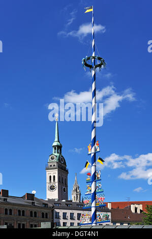 Maypole on Viktualienmarkt market against blue sky with clouds, steeple of the Church of St. Peter at the back, Munich, Bavaria Stock Photo