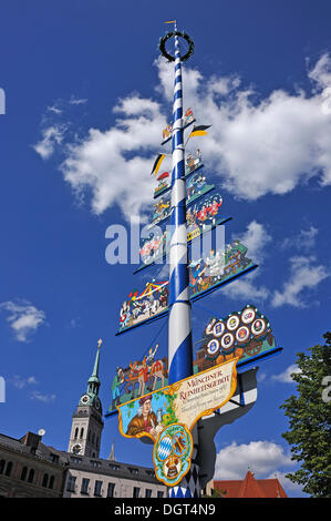 Maypole on Viktualienmarkt market against blue sky with clouds, steeple of the Church of St. Peter at the back, Munich, Bavaria Stock Photo