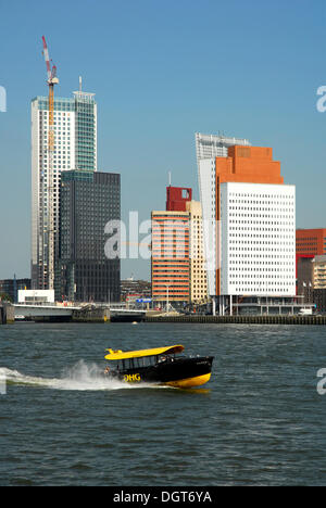 Small watertaxi ferry boat on the Nieuwe Maas River, modern architecture at the Wilhelminapier at back, Rotterdam, Zuid-Holland Stock Photo