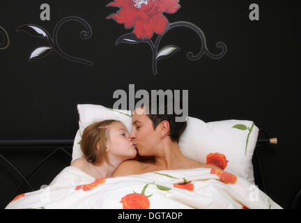 Mother, 35 years, and daughter, 9 years, in bed Stock Photo