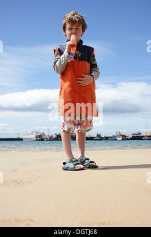 Boy eating ice lolly on beach Stock Photo