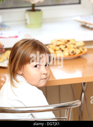 Little girl eats at the table Stock Photo